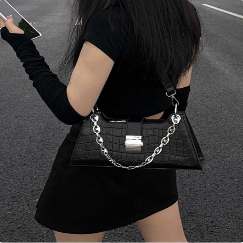 Chic black Baguette Handbag with chain detail, worn by a woman in stylish attire, showcasing its elegant faux leather design.