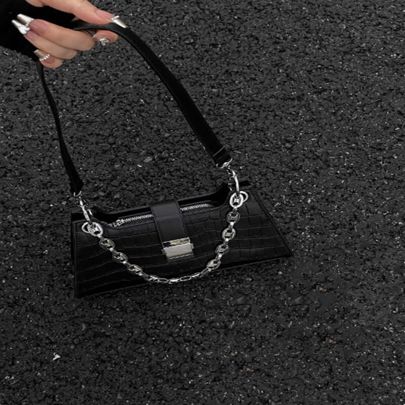 Black Baguette Handbag with chain detail on textured ground, showcasing faux leather and medium size perfect for essentials.
