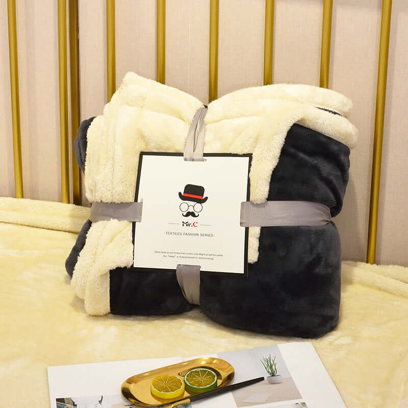 Cozy Flannel Plush Blanket in cream and black, elegantly tied with a ribbon on a soft bed setting.
