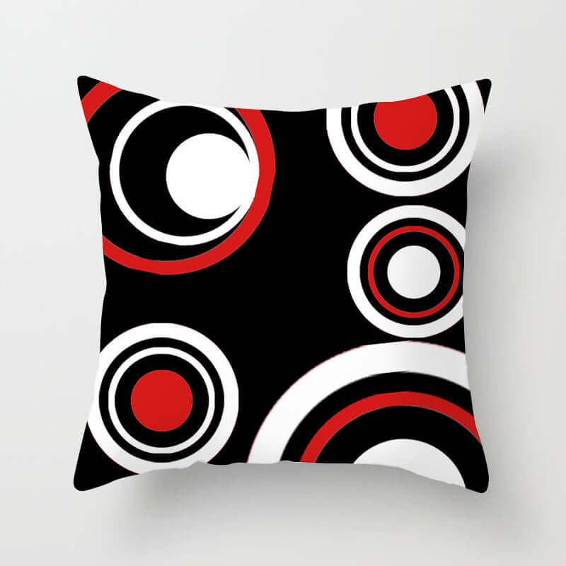 Decorative pillow for sofa featuring bold red, black, and white circular patterns on a sleek background.