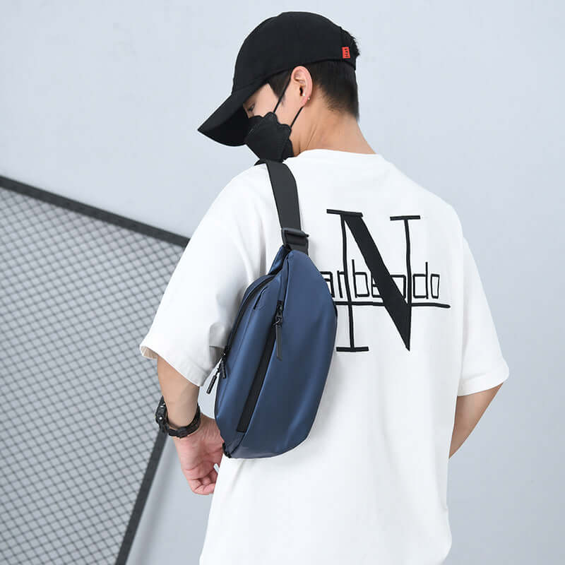 Man wearing a sleek blue high capacity waist bag made of waterproof fabric, designed for active lifestyles.