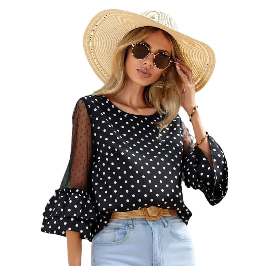Woman wearing a Black Polka Dot Sheer Blouse with 3/4 bell sleeves, paired with a straw hat and sunglasses for a chic summer look.