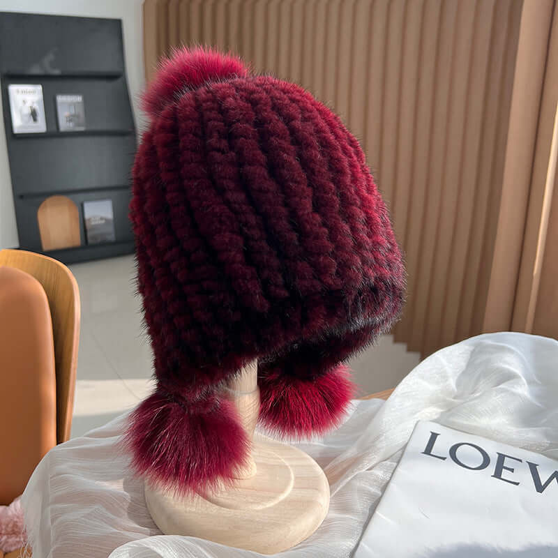 Stylish Ear Muffs Hat in burgundy with fur pom-poms, perfect for staying warm and chic during winter.
