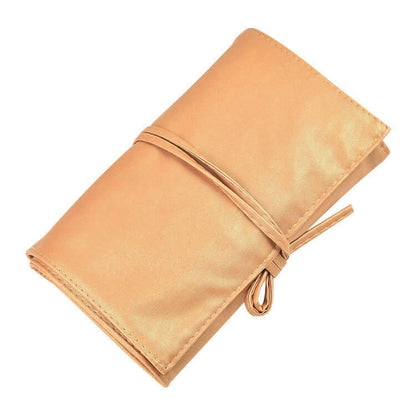 Portable gold case for kit of makeup brushes, closed and tied, ideal for travel and storage.