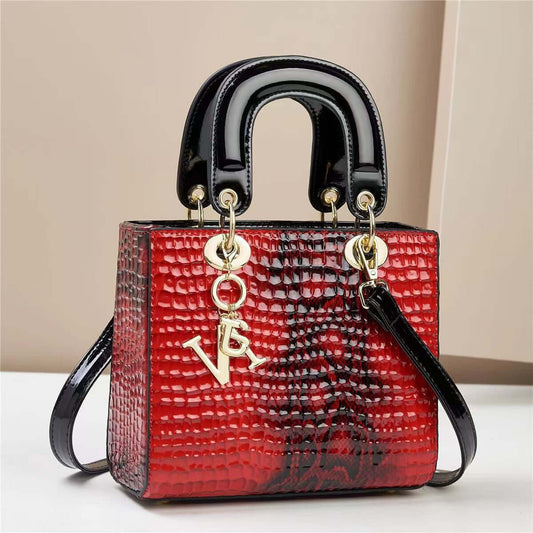 Red crocodile pattern fashion handbag with black handle and gold accents.