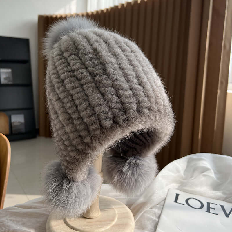 Cozy grey Ear Muffs Hat with fluffy pom-poms, perfect for winter warmth and style.