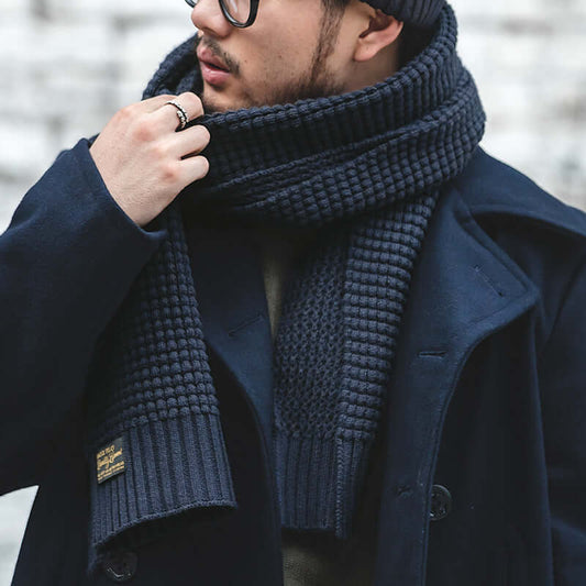 Fashionable wool knitted scarf worn by a stylish man in winter attire, emphasizing warmth and style. Perfect accessory for cold weather.